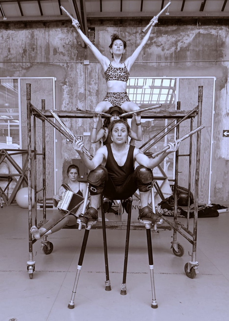 Una figura disfrazada, posiblemente un caballero, sobre zancos, en una habitación poco iluminada con luz azul.